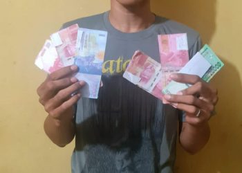 SF memegang uang palsu, saat berada di Mapolres Simalungun. (Foto: Wahanainfo.com)