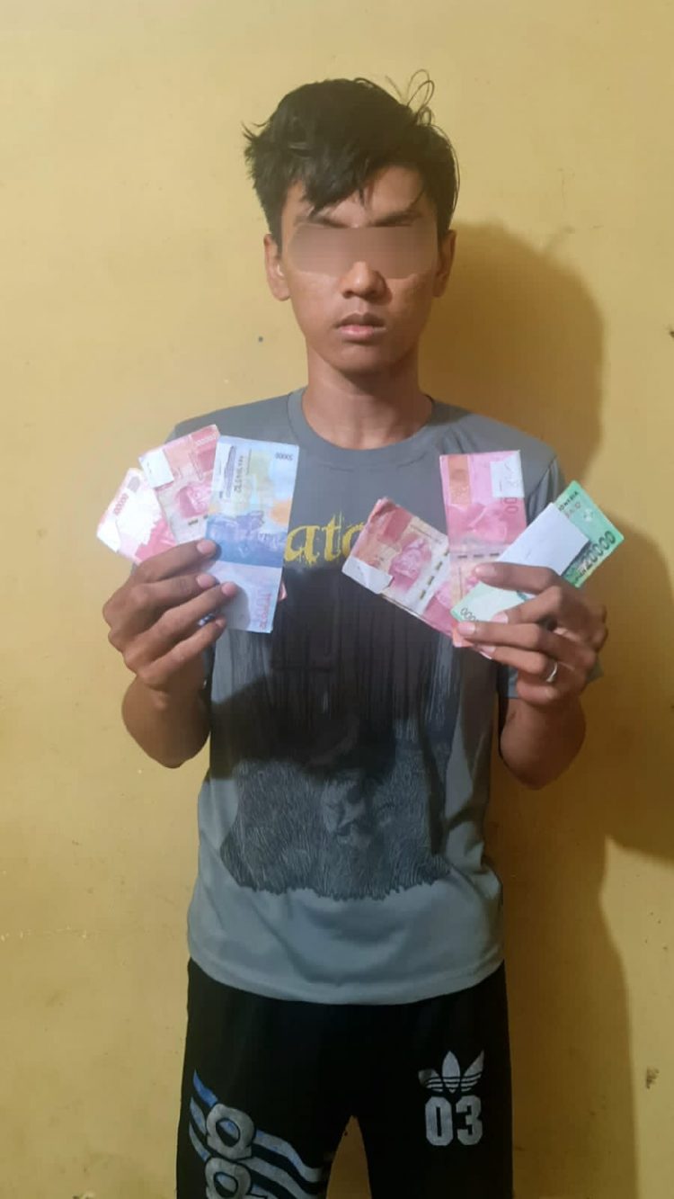 SF memegang uang palsu, saat berada di Mapolres Simalungun. (Foto: Wahanainfo.com)